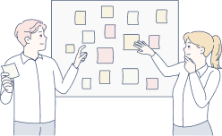 女性と男性が壁に貼っている付箋を触っている